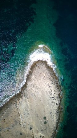 Stunning aerial image showcasing the rugged coastline of Prasonisi, Greece with clear turquoise waters.